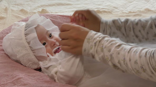 Cute baby model wearing a white lace baby dress.