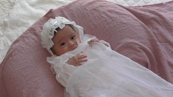 Cute baby model wearing a white lace baby dress.
