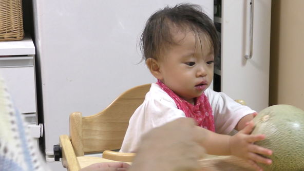 When the mom is going to cut a melon, as avoid being taken to the mom, baby from the baby chair table will get dropped the melon.